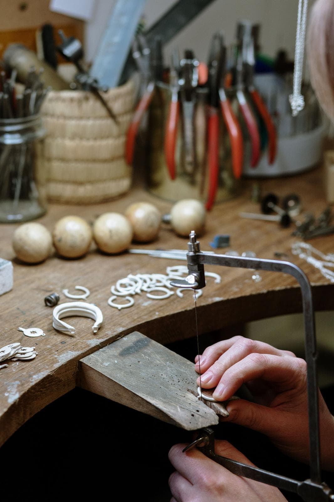 A goldsmith piercing a silver piece with a saw at the Brighton workshop bench